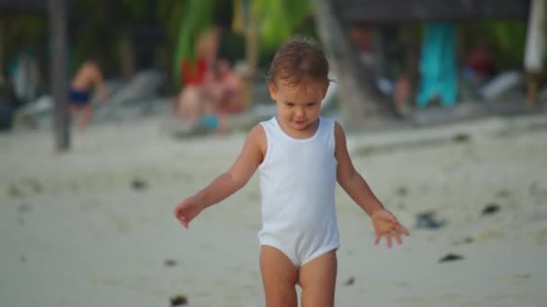 Feche o retrato do bebê bonito. Cabelo soprando no vento na praia em câmera lenta. Ela está sorrindo e atraente — Vídeo de Stock