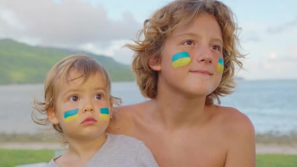 우크라이나 전쟁의 자녀들. 우크라이나 에서온 소년 소녀들은 미래를 바라봅니다. 우크라이나 국기가 얼굴에 그려져 있다 — 비디오