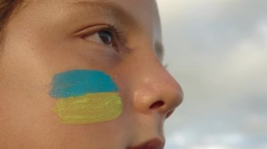 Ukraynalı bir mültecinin portresi. Yüzünde Ukrayna bayrağı var. Ukrayna 'daki savaş çocukları. Savaş mülteci kavramı