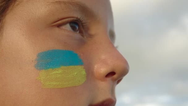 Ukraynalı bir mültecinin portresi. Yüzünde Ukrayna bayrağı var. Ukrayna 'daki savaş çocukları. Savaş mülteci kavramı — Stok video