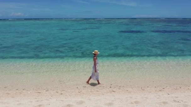 Concetto resort tropicale turismo costiero. Giovane donna in abito bianco cammina sulla spiaggia tropicale. Ampia foto di una ragazza che cammina su una spiaggia di Mauritius con i piedi in acqua — Video Stock