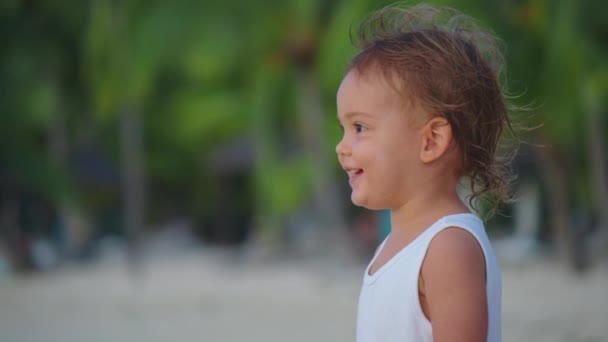 아름다운 아기의 사진을 클로즈업해. 해변에서 느린 동작으로 바람에 나부끼는 머리카락. 그녀는 웃고 매력적 이다 — 비디오