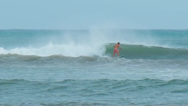 긴 머리를 가진 젊은 남자가 모리셔스 서핑 장에서 대양의 파도를 타고 있다 — 비디오