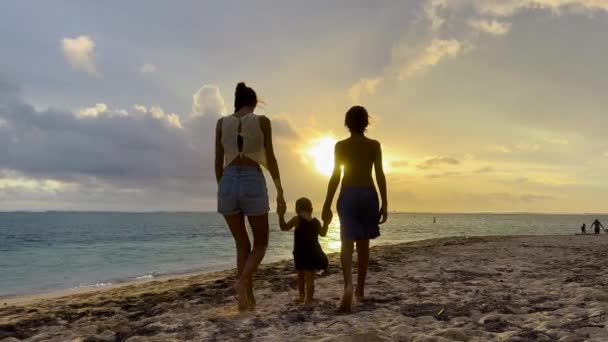Mutlu mutlu bir aile güzel bir gün batımında sahilde yürüyor. — Stok video