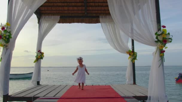 Kleines hübsches Mädchen in weißem Kleid läuft an den Feiertagen. Das Kind trägt ein flauschiges weißes Kleid. Niedliches Baby auf der Hochzeit — Stockvideo