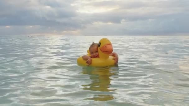 Портрет маленького гарненького малюка, що плаває на надувній качці в Індійському океані. Поняття щасливого дитинства — стокове відео