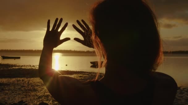 Mãos de menina feliz ao pôr-do-sol. Pôr-do-sol entre as mãos da rapariga. Menina feliz com cabelos longos sonhadoramente estende a mão para o sol — Vídeo de Stock