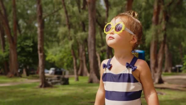 Liebenswertes kleines Mädchen, das an einem warmen und sonnigen Sommertag im Garten tanzt und lächelt — Stockvideo