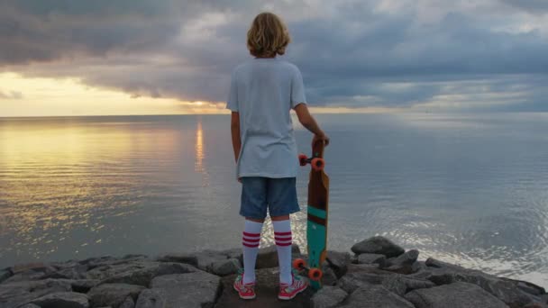 Happy teenager, stylish skater boy holding his skateboard outdoors — Vídeo de Stock