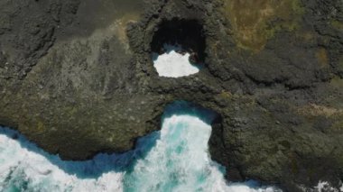 Pont Naturel. Mauritius. Dalgaların yukarıdan görünüşü mavi bir okyanusta kayalara çarpıyor..