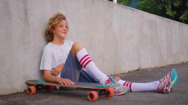Szczęśliwy nastolatek, stylowy łyżwiarz chłopiec trzyma jego deskorolka na zewnątrz — Wideo stockowe