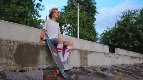 Thoughtful skater guy on urban background. Stylish hipster holding skateboard outdoor. Serious skateboarder staying with skate on city street. Youth sports concept. — Stock Video