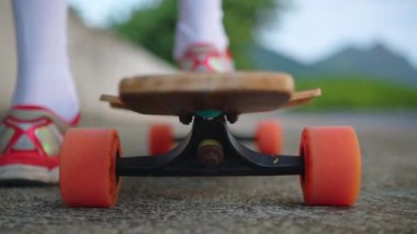Uzun pano yakın çekim. Genç bir kızın bacakları kaykayın üzerinde.