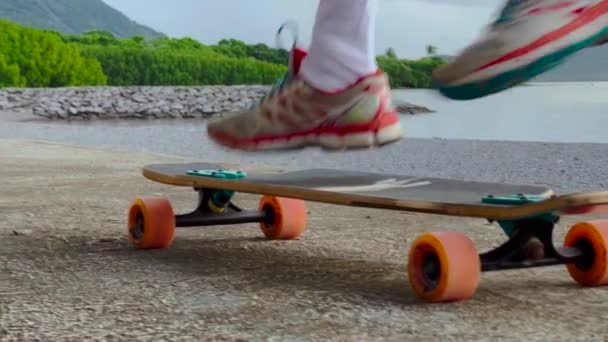 Cheerful little boy with long wavy hair in rides on a long skateboard. Learns to do tricks — Video Stock