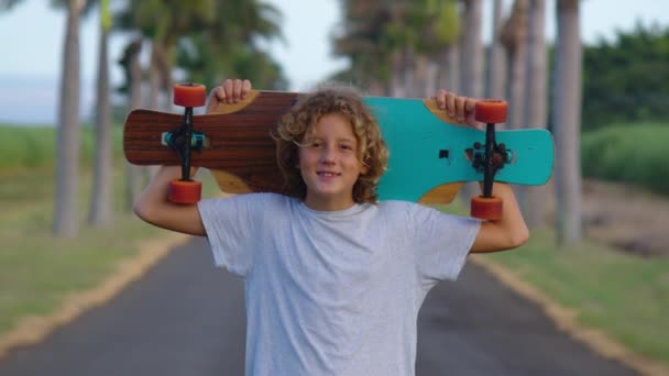 Portrait Junge mit einem Longboard auf einer schönen Straße. Teenager skateboarden auf den Straßen der Stadt — Stockvideo