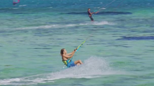 Young kiteboarder surfing di Mauritius melompat sambil naik di sekitar laguna pirus. Kitesurfer memerciki air laut yang berkaca saat berkendara di Mauritius — Stok Video