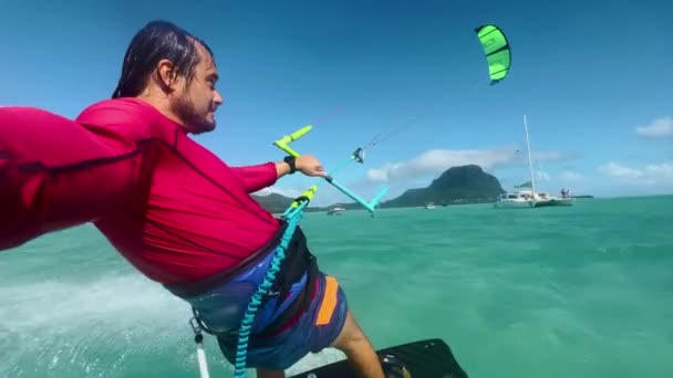 Giovane kiteboarder surf a Mauritius mentre cavalca intorno alla laguna turchese. Kitesurfer spruzza acqua cristallina dell'oceano mentre cavalca a Mauritius — Video Stock