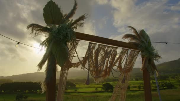 Iluminação de luzes de corda festiva na decoração do arco boho tipi no local da cerimônia de casamento ao ar livre. Vintage corda luzes bulbo guirlandas brilhando acima cadeiras no verão casamento rural. — Vídeo de Stock