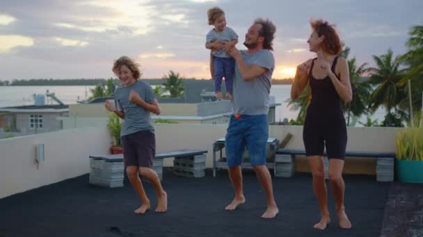家人们在房顶上跳舞 兴奋的年轻父母和孩子们一起跳舞 一群人在夕阳西下嬉笑着 高质量的4K镜头 — 图库视频影像