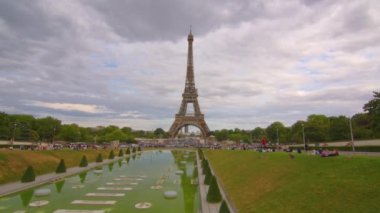Eiffel Tower on Champs de Mars in Paris, France. Blue cloudy sky at summer day with green lawn. High quality 4k footage