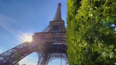 Eiffel Tower on Champs de Mars in Paris, France. Blue cloudy sky at summer day with green lawn. High quality 4k footage
