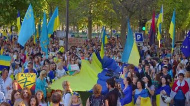Paris, France, August 24 2022: People protesting against war, crowd waving flags. View of Ukrainian people protest on the streets of Paris against the war, people with flags. Independence Day.