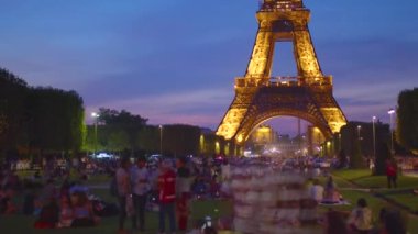 Eiffel Tower on Champs de Mars in Paris time lapse, France. Blue night cloudy sky at summer day with green lawn and people walking around. High quality 4k footage