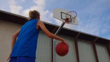 Young athletic male playing basketball outdoors. Young sports men practicing basketball on the outdoor court. High quality 4k footage