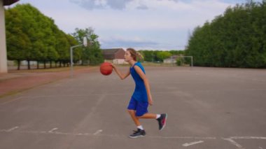 Young athletic male playing basketball outdoors. Young sports men practicing basketball on the outdoor court. High quality 4k footage