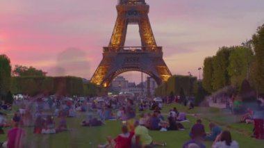 Eiffel Tower on Champs de Mars in Paris time lapse, France. Blue night cloudy sky at summer day with green lawn and people walking around. High quality 4k footage
