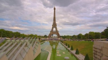 Eiffel Tower on Champs de Mars in Paris, France. Blue cloudy sky at summer day with green lawn. High quality 4k footage