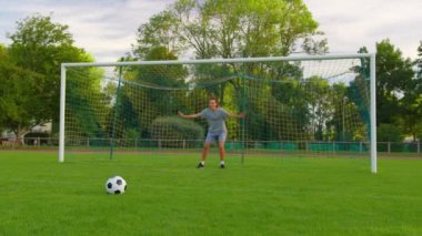 Ailenin parkta futbol oynarken çekilen yavaş çekim. Mutlu ebeveynler ve çocuklar yeşil çayırda topla oynuyorlar. Neşeli aile yazın dışarıda eğleniyor. Yüksek kalite 4k görüntü