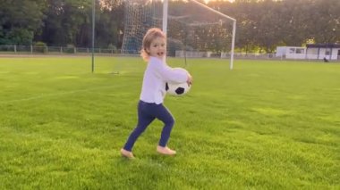 Küçük kız parkta top oynuyor. Mutlu aile çocuğu hayali konsepti. Bebek doğa parkında futbol oynuyor. Eğlenceli bebek topa vuruyor. Mutlu aile çocukluğu. Yüksek kalite 4k görüntü