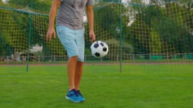 Top Sporcu 'nun kontrolünde. Futbol topu olan çocuk. Çocuk futbol topuyla hokkabazlık yapıyor. Çocuk futbol maçı rüyası. Parkta spor eğitimi. Çocuk top çeviriyor. Sağlıklı bir yaşam tarzı. Yüksek kalite 4k görüntü