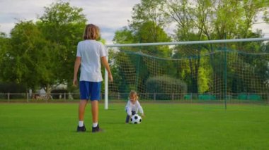 Bir futbol topuyla oynayan iki çocuklu mutlu bir aile. Birbirlerine top atıyorlar. Sahada futbol topuyla mutlu bir aile. Yüksek kalite 4k görüntü