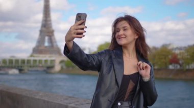 Paris 'te Eyfel kulesi parkında ve caddelerde şık kıyafetler giyen genç bir kadının sinematik görüntüleri. Avrupa turizmi ve başkent şehirlerine seyahat kavramları.