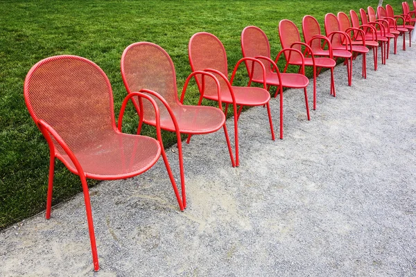 Cadeiras de metal vermelho e grama verde — Fotografia de Stock