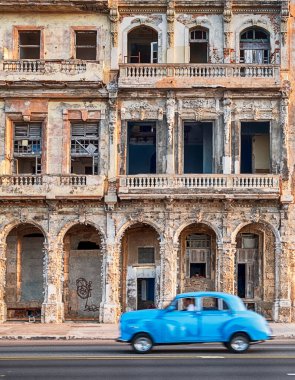 HAVANA, CUBA - 31 Aralık 2019: Anonim bir adam eski bir binanın önündeki Malecon rıhtım yolunda eski bir Amerikan arabasını taksi olarak kullanıyor.