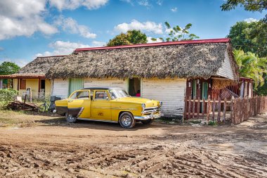 VINALES, CUBA - 26 Aralık 2019: Vinales kasabasındaki yerel bir Küba restoranının önünde taksi olarak çalışan klasik sarı bir Amerikan arabası bekliyor..