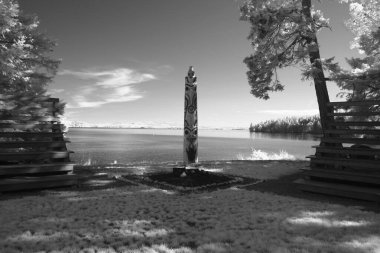 Vampir tiyatrosunun açık ucunda, yaz kampında tören için kullanılan oturaklı bir totem direği. Arka planda Puget Sound 'un suyu var..