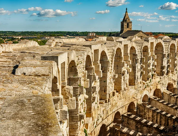 Arlesの古いローマ時代のアリーナを囲む石造りの柱廊の眺めには 市内のいくつかの教会の尖塔が含まれています — ストック写真