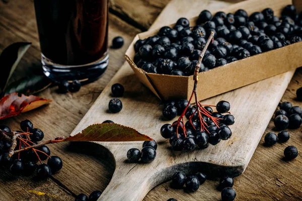 Fresh aronia berries and berry juice in a glass