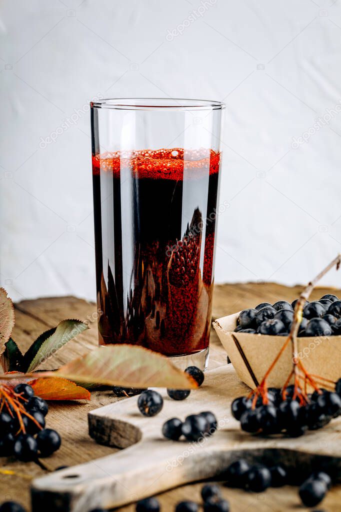 Fresh aronia berries and berry juice in a glass