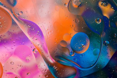 Su yüzeyindeki yağ damlacıklarının hareketine yakın çekim. Su yüzeyindeki yağ damlalarının renkli ve soyut makro arkaplanı