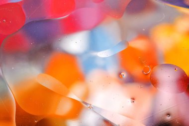 Su yüzeyindeki yağ damlacıklarının hareketine yakın çekim. Su yüzeyindeki yağ damlalarının renkli ve soyut makro arkaplanı