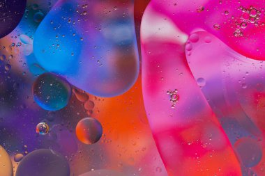 Su yüzeyindeki yağ damlacıklarının hareketine yakın çekim. Su yüzeyindeki yağ damlalarının renkli ve soyut makro arkaplanı