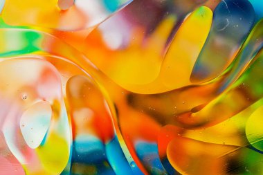 Su yüzeyindeki yağ damlacıklarının hareketine yakın çekim. Su yüzeyindeki yağ damlalarının renkli ve soyut makro arkaplanı