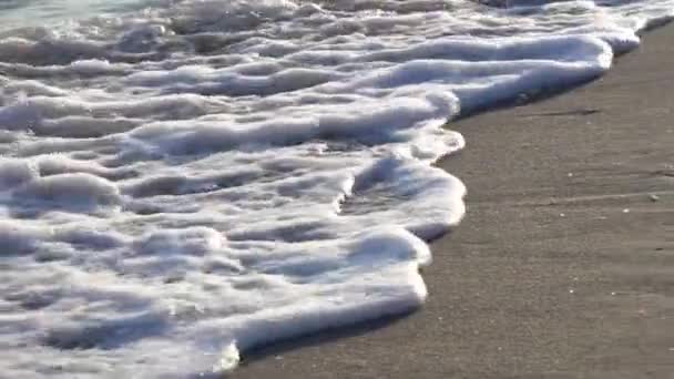 沙滩上的海浪形成的白色泡沫，是一个冲浪和放松夏季旅行的好地方 — 图库视频影像