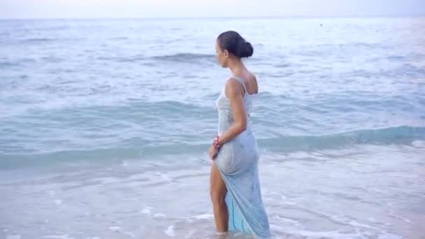 Fantastisk brunett kvinna i klänning in i havet vågigt vatten på ön kusten, promenader på vattnet — Stockvideo