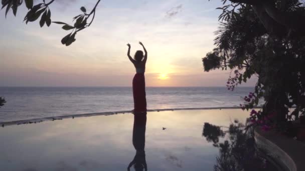 Tranquilo silhueta meditativa de corpo de mulher elegante dança solitária na água calma, pôr do sol à beira-mar — Vídeo de Stock